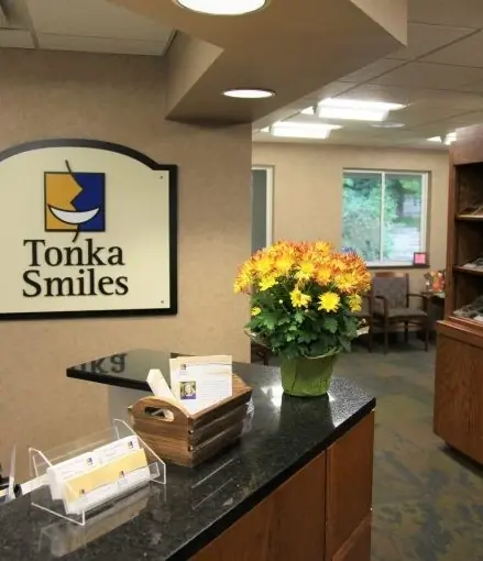The Tonka Smiles reception desk, with the practice's sign and a vase of yellow flowers.
